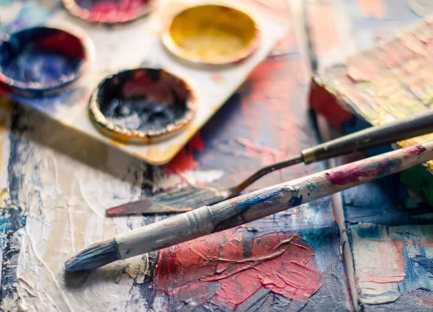A close up of a paint palette with a paintbrush
